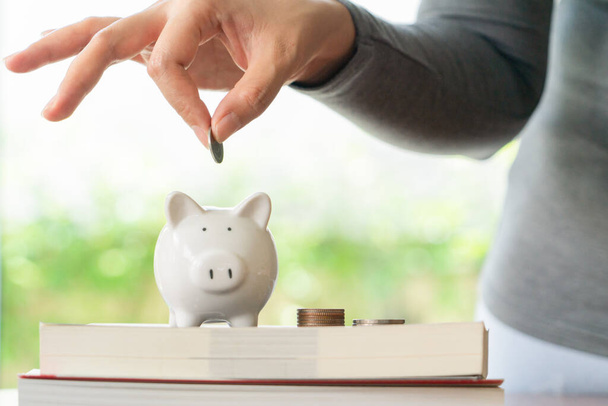 woman putting a coin to saving piggy bank, saving money for education concept - Photo, Image