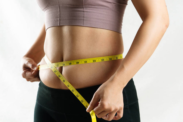 молодая женщина измеряет ее чрезмерное живота жира талии с помощью ленты, женщина диеты концепции образа жизни
 - Фото, изображение
