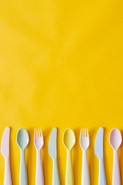 Colorful fork, spoon and knife on yellow background with empty space for text. - Foto, immagini