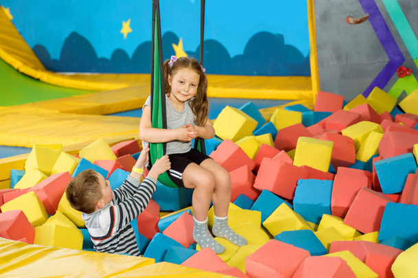 Children playing with soft cubes in the dry pool in play center. playground with foam blocks in trampoline club - Фото, изображение