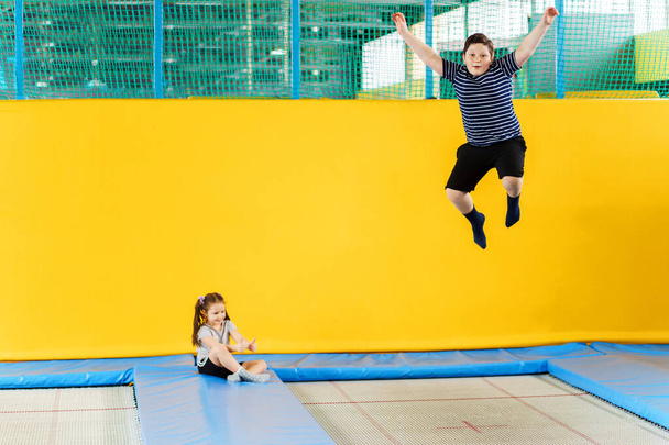 Счастливые улыбающиеся маленькие дети прыгают на крытом батуте в развлекательном центре
 - Фото, изображение