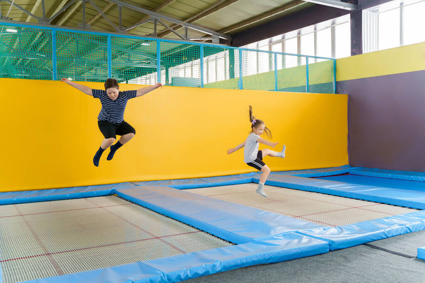 Happy smiling small kids jumping on indoors trampoline in entertainment center - Foto, immagini