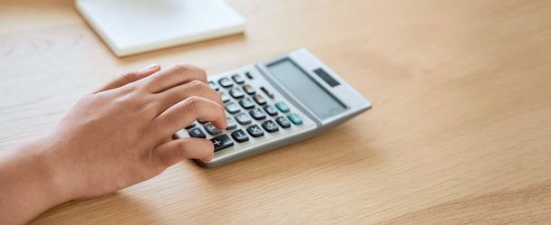 Vrouw pers calculator om inkomenskosten te berekenen en plannen voor het uitgeven van geld op kantoor. - Foto, afbeelding