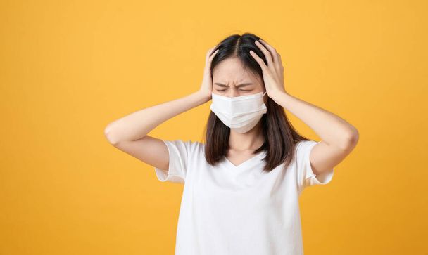 Ázsiai nők viselnek maszkot, hogy megvédje a betegség és a fejfájás egy vírus narancssárga alapon. - Fotó, kép