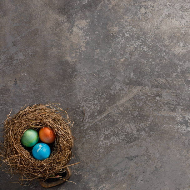 Easter eggs in a bird's nest on a textural background. Easter celebration concept. Copy space. Flat lay. - Photo, image