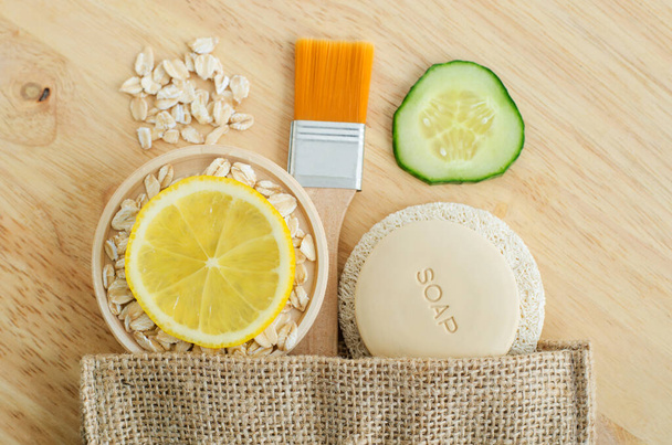 Oatmeal, lemon and cucumber slices, soap bar and make-up brush. Ingredients for preparing homemade mask. Natural beauty treatment recipe, zero waste concept. Top view, copy space - Foto, Imagem