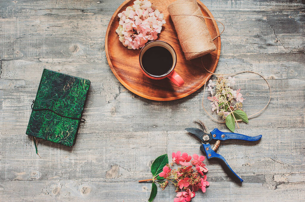herfst of zomer tuintafel bovenaanzicht met schetsboek, koffie, gedroogde hortensia bloemen en tuin snoeier - Foto, afbeelding
