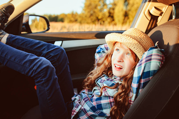 happy child girl relaxing in car during summer road trip. Exploring new places, traveling on summer vacations. - 写真・画像
