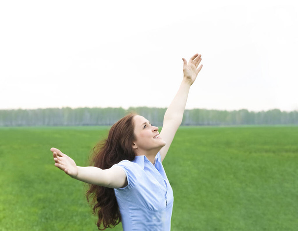 Roodharige krullende vrouw. gelukkig glimlachend vrolijk met handen omhoog dansen op het veld in de zomer tijdens de vakantie. Mooi jong vrouwelijk model.Jonge vrouw buiten.Vrijheid en lente concept. - Foto, afbeelding