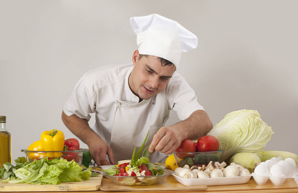 Portrait of young chef  cooking vegetables  in restaurant kitchen, copy space.  - Fotó, kép