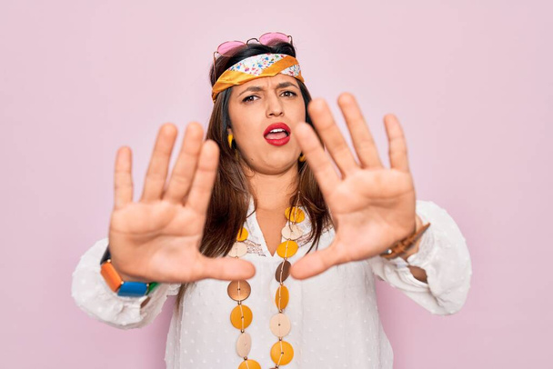 Mladý hispánský hippie žena nosí módní boho styl a sluneční brýle přes růžové pozadí dělat stop gesto s dlaněmi, naštvaný a frustrovaný výraz - Fotografie, Obrázek