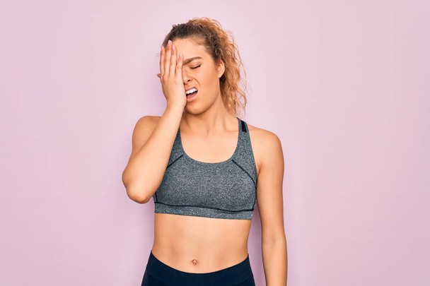 Young beautiful blonde sportswoman with blue eyes doing exercise wearing sportswear Yawning tired covering half face, eye and mouth with hand. Face hurts in pain. - Photo, Image