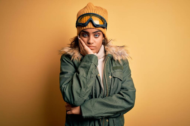 Young african american afro skier girl wearing snow sportswear and ski goggles thinking looking tired and bored with depression problems with crossed arms. - Фото, зображення