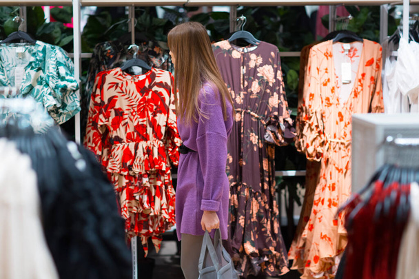 Mujer joven elige la ropa en la tienda
 - Foto, imagen