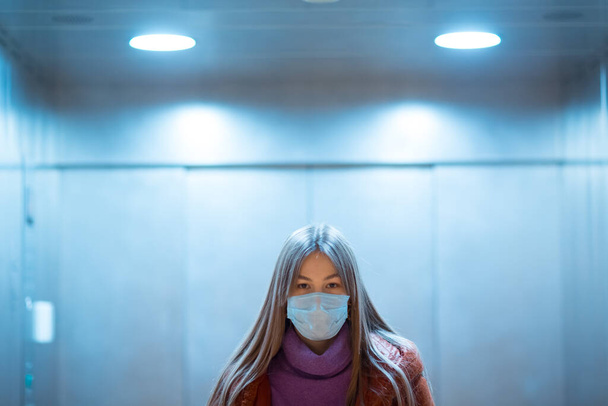 Giovane donna asiatica in piedi in ascensore in maschera medica. Concetto di pandemia di Coronavirus COVID-19
. - Foto, immagini