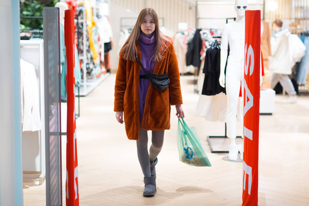 Jonge vrouw gaat door een beveiliging anti-diefstal kader in een winkel - Foto, afbeelding