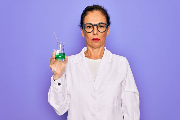 Donna scienziata anziana di mezza età che indossa un camice da laboratorio con una provetta di ricerca con un'espressione fiduciosa sul viso intelligente che pensa seriamente
 - Foto, immagini