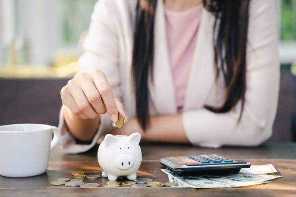 Großaufnahme einer Geschäftsfrau, die Geldmünzen in Sparschweine steckt, um Geld zu sparen. Geld sparen und Finanzkonzept - Foto, Bild