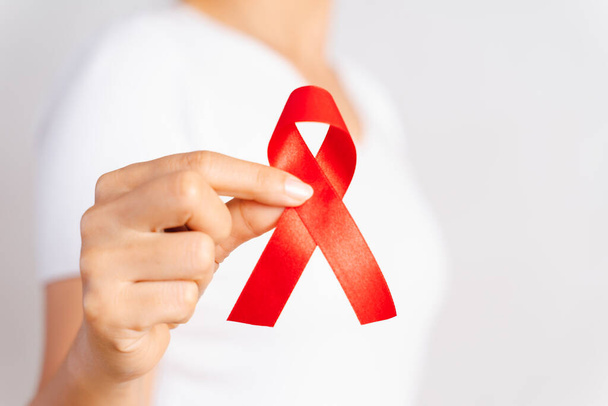 Closeup žena ruku hospodářství červenou stužku Hiv, svět Aids den povědomí pásu. Koncepce zdravotnictví a medicína. - Fotografie, Obrázek