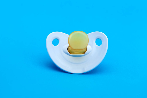 a blue baby pacifier made of soft silicone  isolated on blue background front view with copy space. - Foto, afbeelding
