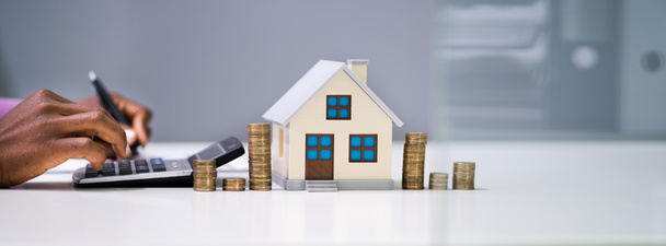 Biznesmen Obliczanie podatku według modelu domu i monet - Zdjęcie, obraz