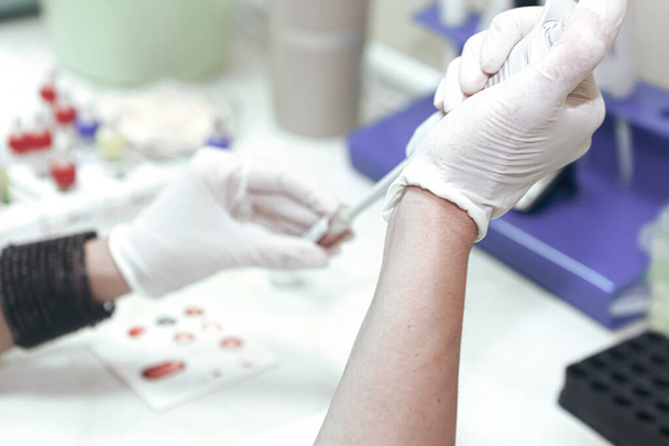 Naukowiec pracujący w swoim laboratorium. Badanie krwi jest to analiza laboratoryjna przeprowadzana na próbce krwi, która jest zwykle pobierana z żyły w ramieniu przy użyciu igły podskórnej lub za pomocą kłucia palców.. - Zdjęcie, obraz
