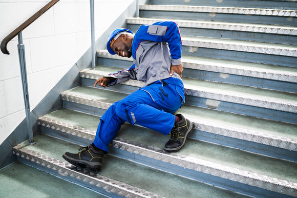 Εργάτης ξαπλωμένος στις σκάλες μετά από ατύχημα ολίσθησης και πτώσης - Φωτογραφία, εικόνα