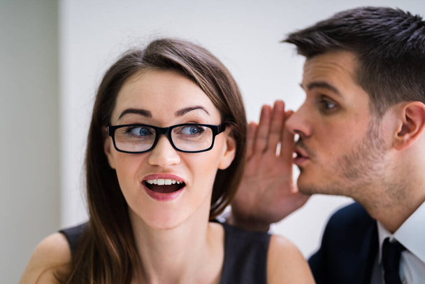 Close-up Of Businessman Whispering Into Female Partner's Ear - 写真・画像