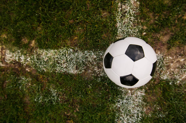 スタジアムの芝の白い線に置かれた古典的なサッカーボール、典型的な黒と白のパターン。緑の芝生の芝生の上の伝統的なサッカーボールコピースペース. - 写真・画像