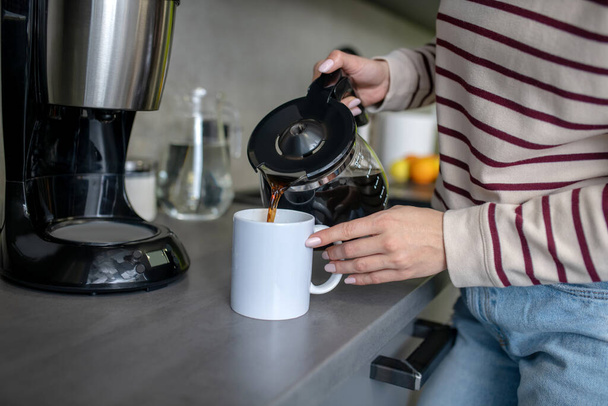 Woman hands pouring coffee into white cup - Photo, image