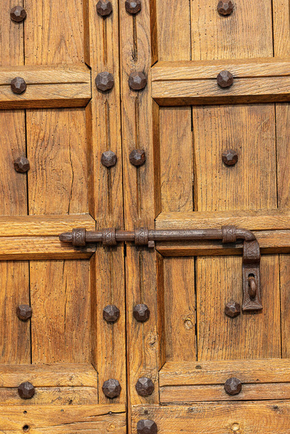 Primer plano de una vieja puerta de madera marrón con un gran pestillo de hierro forjado y clavos. Verona provincia, Véneto, Italia, Europa
 - Foto, imagen