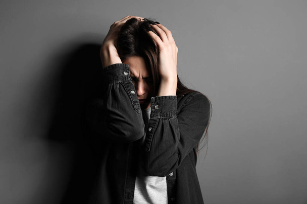 Depressed young woman on grey background - Фото, изображение