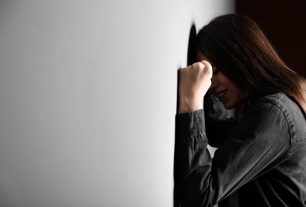 Mujer joven deprimida cerca de la pared gris
 - Foto, imagen
