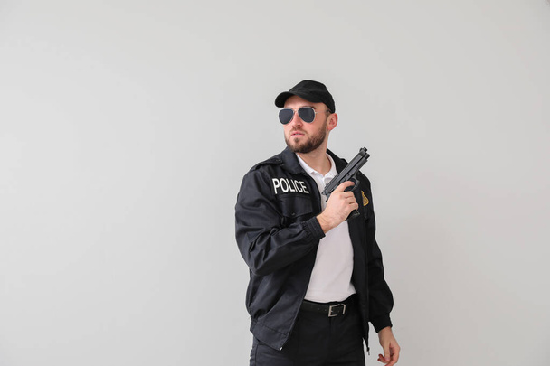Male police officer with gun on light background - Photo, Image