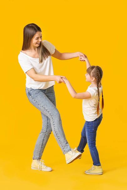 Happy mother and her little daughter dancing against color background - Valokuva, kuva