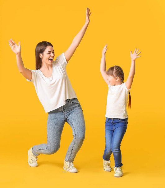 Happy mother and her little daughter dancing against color background - Foto, immagini