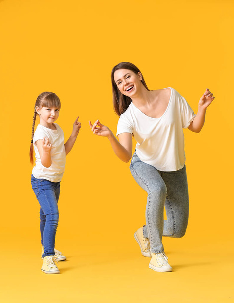 Šťastná matka a její malá dcera tančí na barevném pozadí - Fotografie, Obrázek