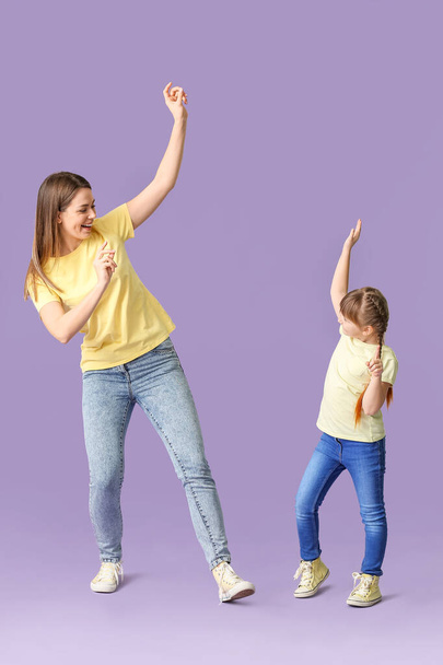 gelukkig moeder en haar dochtertje dansen tegen kleur achtergrond - Foto, afbeelding