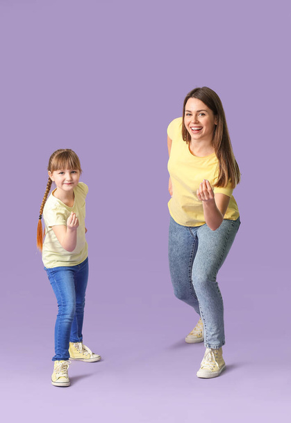 Happy mother and her little daughter dancing against color background - Foto, imagen