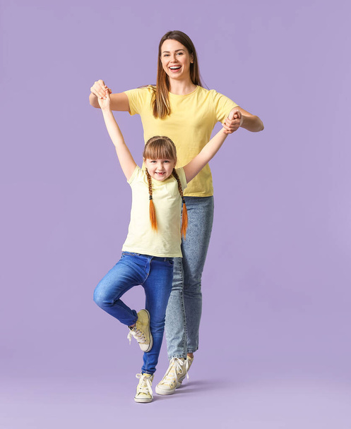 glückliche Mutter und ihre kleine Tochter tanzen vor farbigem Hintergrund - Foto, Bild