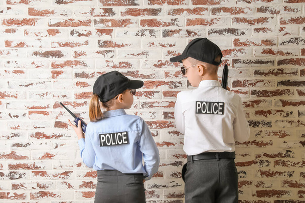Lindos pequeños oficiales de policía sobre fondo de ladrillo
 - Foto, Imagen