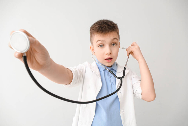 Cute little doctor with stethoscope on grey background - Zdjęcie, obraz