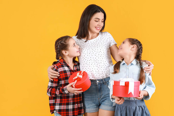 Mujer y sus hijitas con regalos sobre fondo de color. Celebración del Día de la Madre
 - Foto, imagen