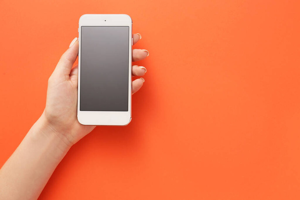 Жіноча рука з мобільним телефоном на кольоровому фоні
 - Фото, зображення