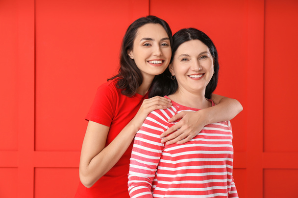 Porträt der erwachsenen Tochter und ihrer Mutter auf farbigem Hintergrund - Foto, Bild
