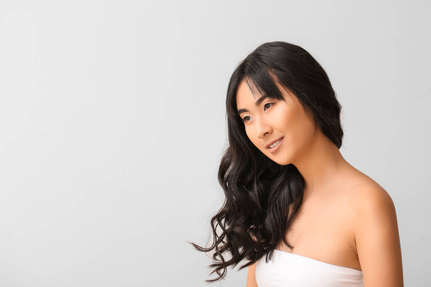 Joven mujer asiática con hermoso pelo largo sobre fondo claro
 - Foto, Imagen
