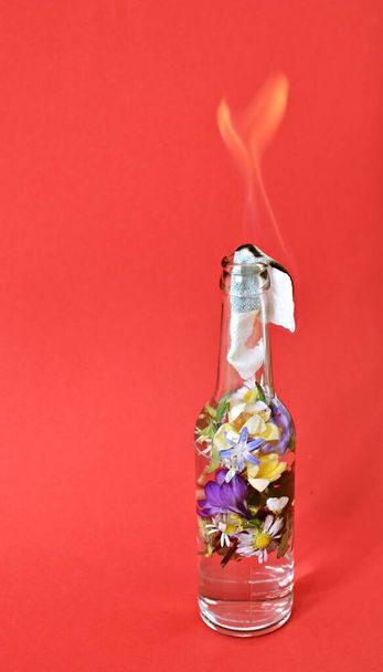 Coquetel Molotov cheio de flores coloridas - resistência amorosa retratada sobre uma superfície ardente cheia de flores - luta ecológica abstrata
 - Foto, Imagem