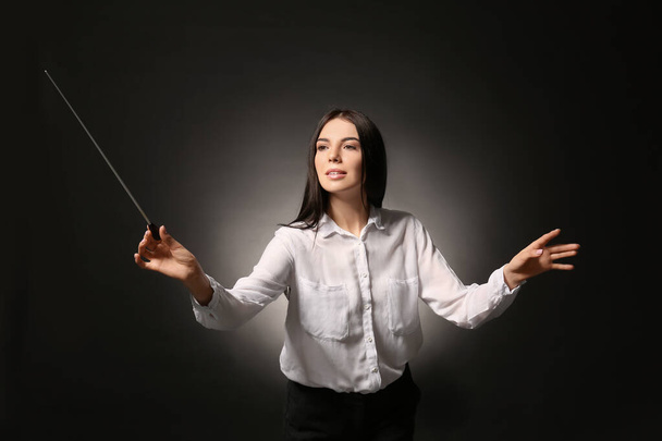 Mladý ženský dirigent na tmavém pozadí - Fotografie, Obrázek