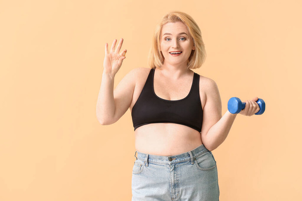 Woman with weight loss pill and dumbbell on color background - Fotoğraf, Görsel
