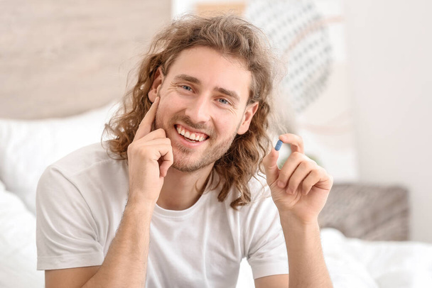 Młody mężczyzna z doustnymi lekami na zaburzenia erekcji w sypialni - Zdjęcie, obraz